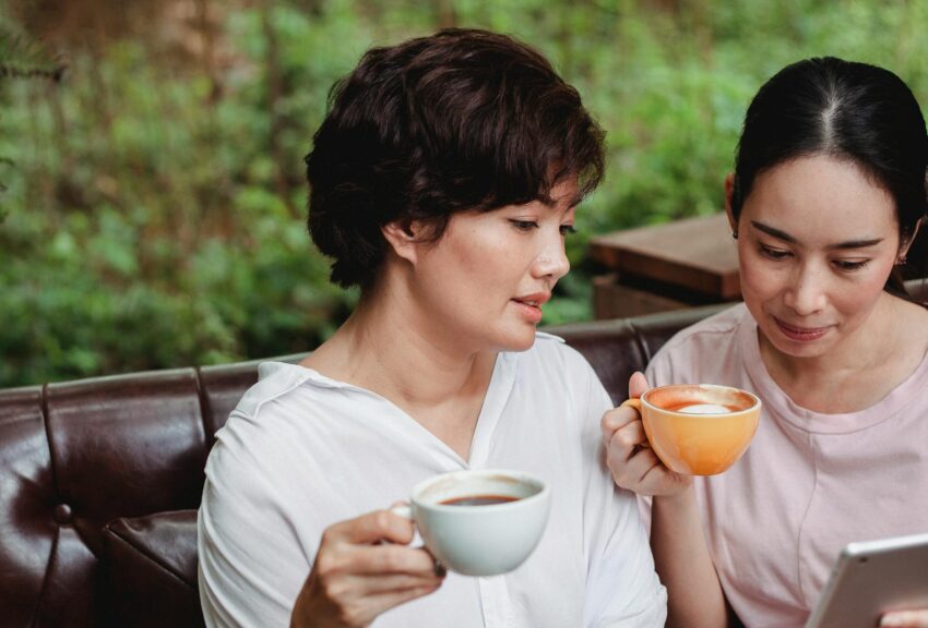 asian women sitting with cups of coffee in garden