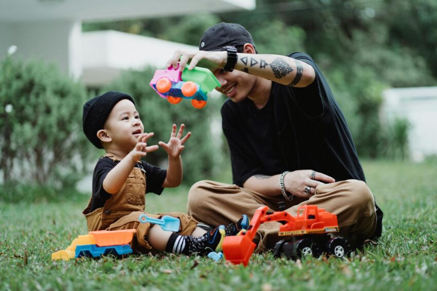 young father and son playing with toy cars outside